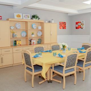 A cozy dining room with a yellow tablecloth and neatly arranged furniture.