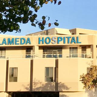 The front view of Alameda Hospital with its name displayed on the building.