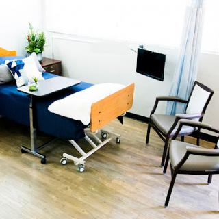 A well-designed hospital room featuring a patient bed, seating area, and natural light.