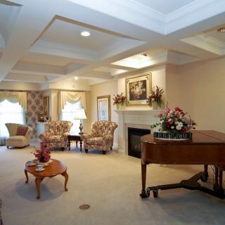 A cozy living room with elegant furniture, a grand piano, and a fireplace.