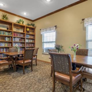 A cozy reading room with bookshelves, tables, and chairs.