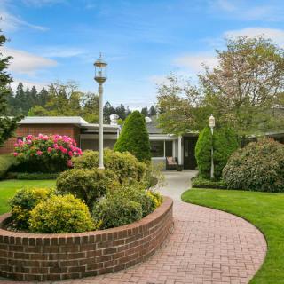 A beautifully landscaped garden with a curving brick pathway and lush greenery.
