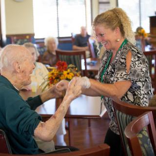 A caregiver engaging warmly with an elderly resident, fostering connection and support in a community setting.