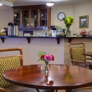 A cozy cafe interior with wooden tables, cushioned chairs, and floral decorations.