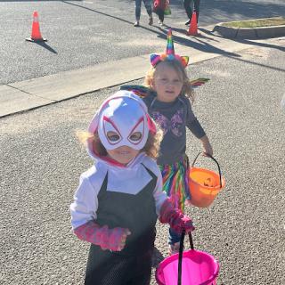 Two children dressed in costumes enjoying a Halloween trick-or-treating event.