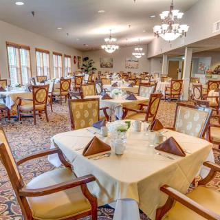 Elegant dining room with neatly set tables and ornate chandeliers.