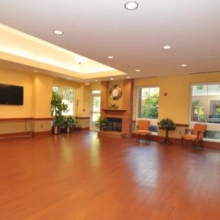 Spacious lobby with wood flooring, seating area, and a fireplace.