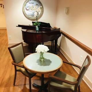 A cozy corner with a piano and a small round table with flowers.
