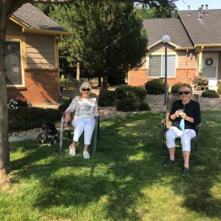 Two people sitting on chairs in a sunny backyard.