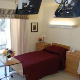 A neatly arranged hospital room with a bed, bedside table, and decorative flowers.
