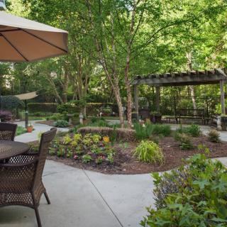 A serene garden patio area with outdoor seating and lush greenery.