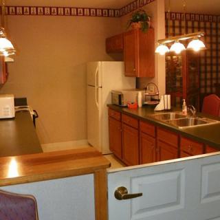 A cozy kitchen with wooden cabinets, a refrigerator, and warm lighting.