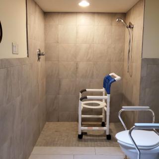 An accessible bathroom with a shower chair and handrails, designed for ease of use and safety.