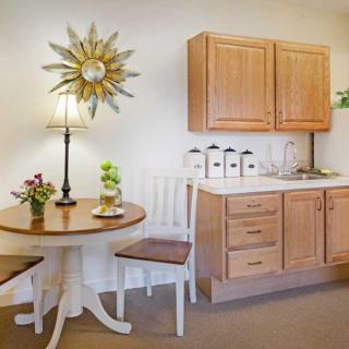 A cozy kitchen corner with a small round dining table and chairs, complemented by wooden cabinets and decorative items.