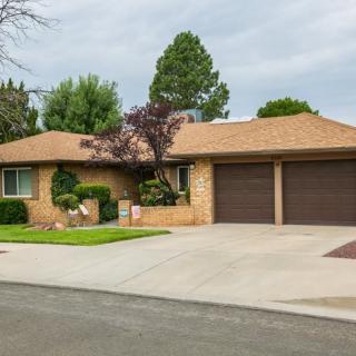 A suburban brick house with a neatly landscaped front yard and a two-car garage.