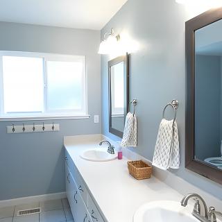 A modern bathroom with dual sinks, mirrors, and a window illuminating the space.