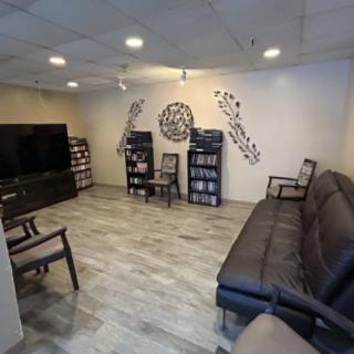 A cozy living room with a large sofa, chairs, bookshelves, and a television.