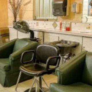 Interior view of a beauty salon with green chairs and hairdressing equipment.
