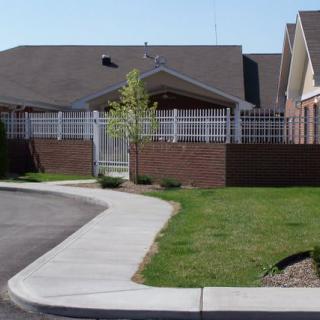 A suburban house with a driveway, fence, and a well-maintained lawn.