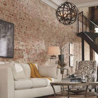 A modern loft-style living room with a brick wall, cozy sofa, and stylish staircase.