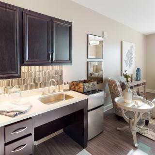 A modern kitchenette with dark cabinets, a sink, and cozy dining area.