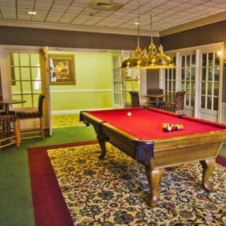 A cozy game room featuring a red-felt pool table under warm lighting.