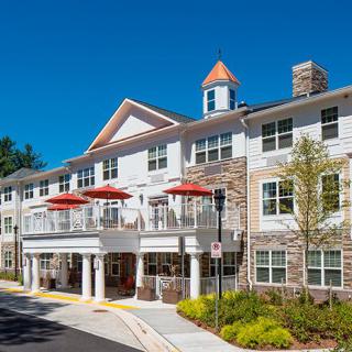A modern residential building with balconies and red umbrellas under a clear blue sky.