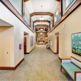 A spacious and well-lit modern hallway featuring wooden accents, seating areas, and decorative artwork.