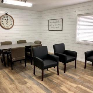 A waiting room with chairs and a large wall clock.