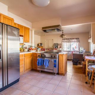 A cozy kitchen with wooden cabinets, a stainless steel refrigerator, and a stove, leading into a bright dining area.