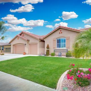 A charming single-story house with a well-maintained front yard and beautiful landscaping under a clear blue sky.