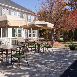 A serene outdoor patio with tables, chairs, and umbrellas set against an autumn backdrop.
