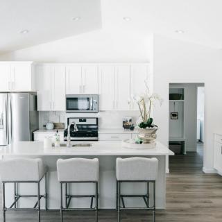 A minimalist modern kitchen with white cabinetry and appliances.