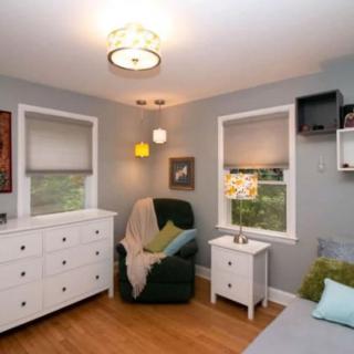 A cozy bedroom with a dresser, armchair, and nightstands.