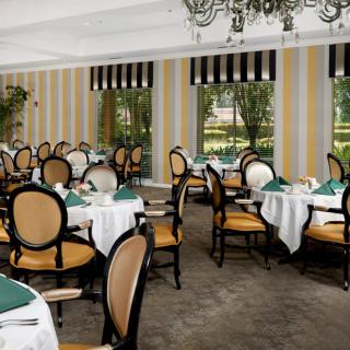 An elegant dining area with neatly arranged tables and chairs, featuring classic decor and a chandelier.