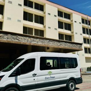A shuttle van parked in front of a hotel building, ready to transport guests.