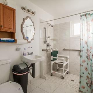 An accessible bathroom equipped with a shower chair and grab bars for safety.