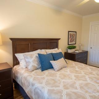 A cozy bedroom with a wooden headboard, patterned bedding, and decorative pillows.
