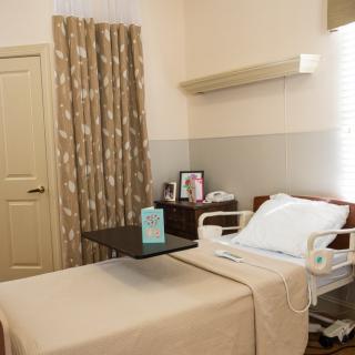 A clean and organized hospital room with a bed, side table, and curtains.