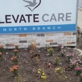 A healthcare facility sign with a flower garden in front.