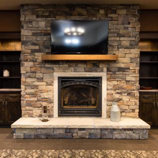A cozy living room with a stone fireplace and a television mounted above it.