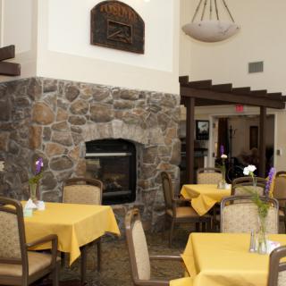 A cozy restaurant interior featuring a stone fireplace and tables with yellow tablecloths.