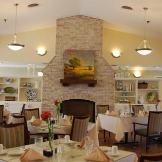 A cozy dining area with elegantly set tables and a central fireplace.