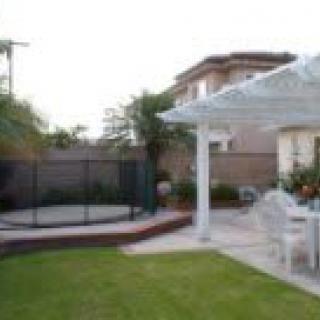 A cozy backyard with a pergola, outdoor furniture, and landscaped lawn.