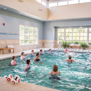 A group of people participating in a water aerobics class in an indoor pool.