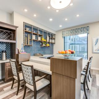 A modern kitchen with a bar area, featuring wood cabinetry and contemporary lighting.