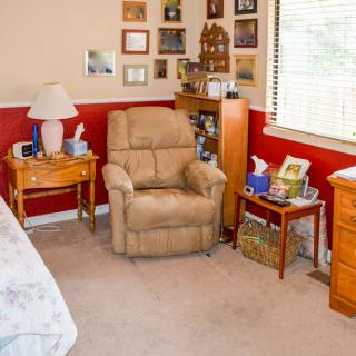 A cozy bedroom corner with a recliner, nightstands, and family photos on the wall.