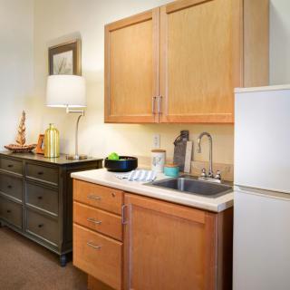 A compact kitchen area with wooden cabinets, a sink, refrigerator, and stylish decor.
