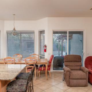A cozy living and dining area featuring a variety of chairs, large windows, and a sliding glass door.