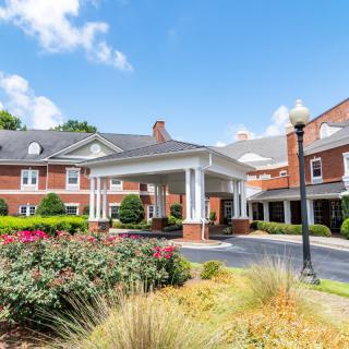 A charming building entrance with a well-maintained garden under a bright blue sky.